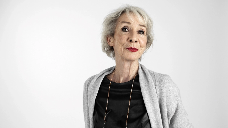Une personne âgée sourit joyeusement à la caméra