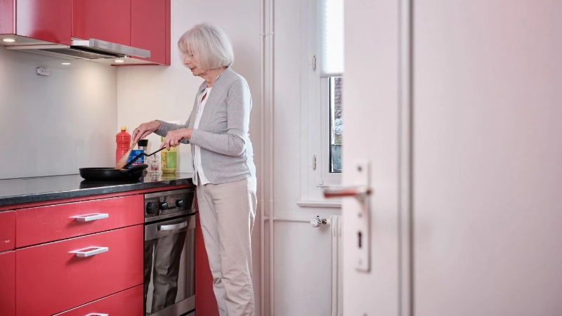 Une femme âgée est debout dans la cuisine et cuisine.