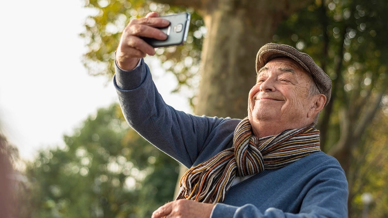 Un uomo anziano si scatta un selfie con il cellulare.