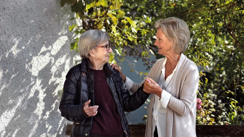 Deux dames âgées discutent ensemble et se tiennent la main.