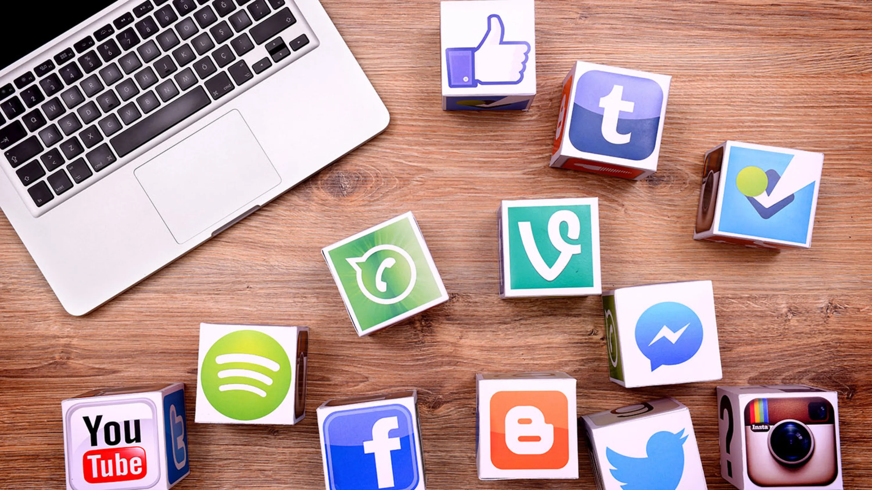 Notebook und Informatiksymbole auf dem Tisch.