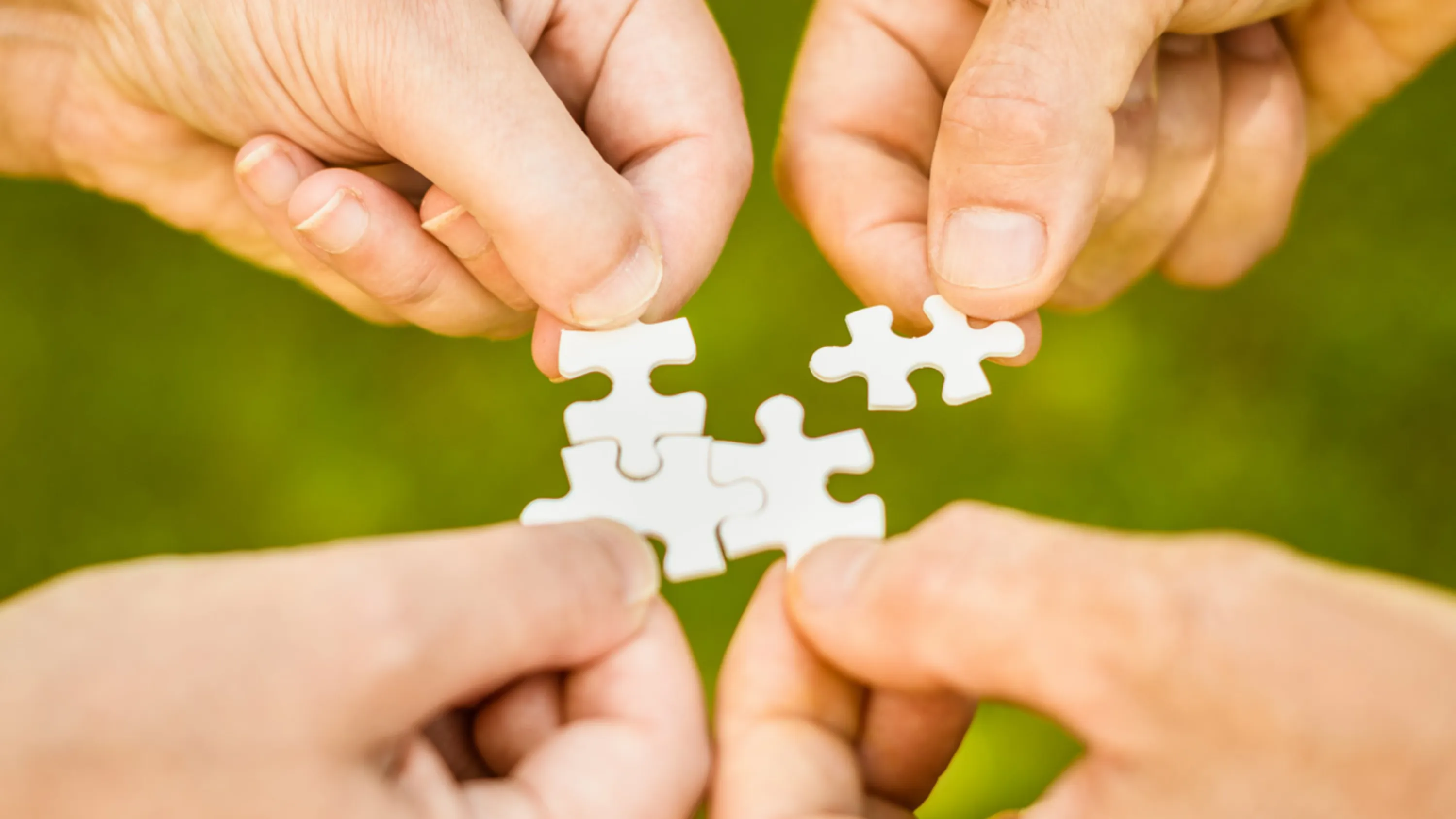 Hände halten Puzzleteile zusammen