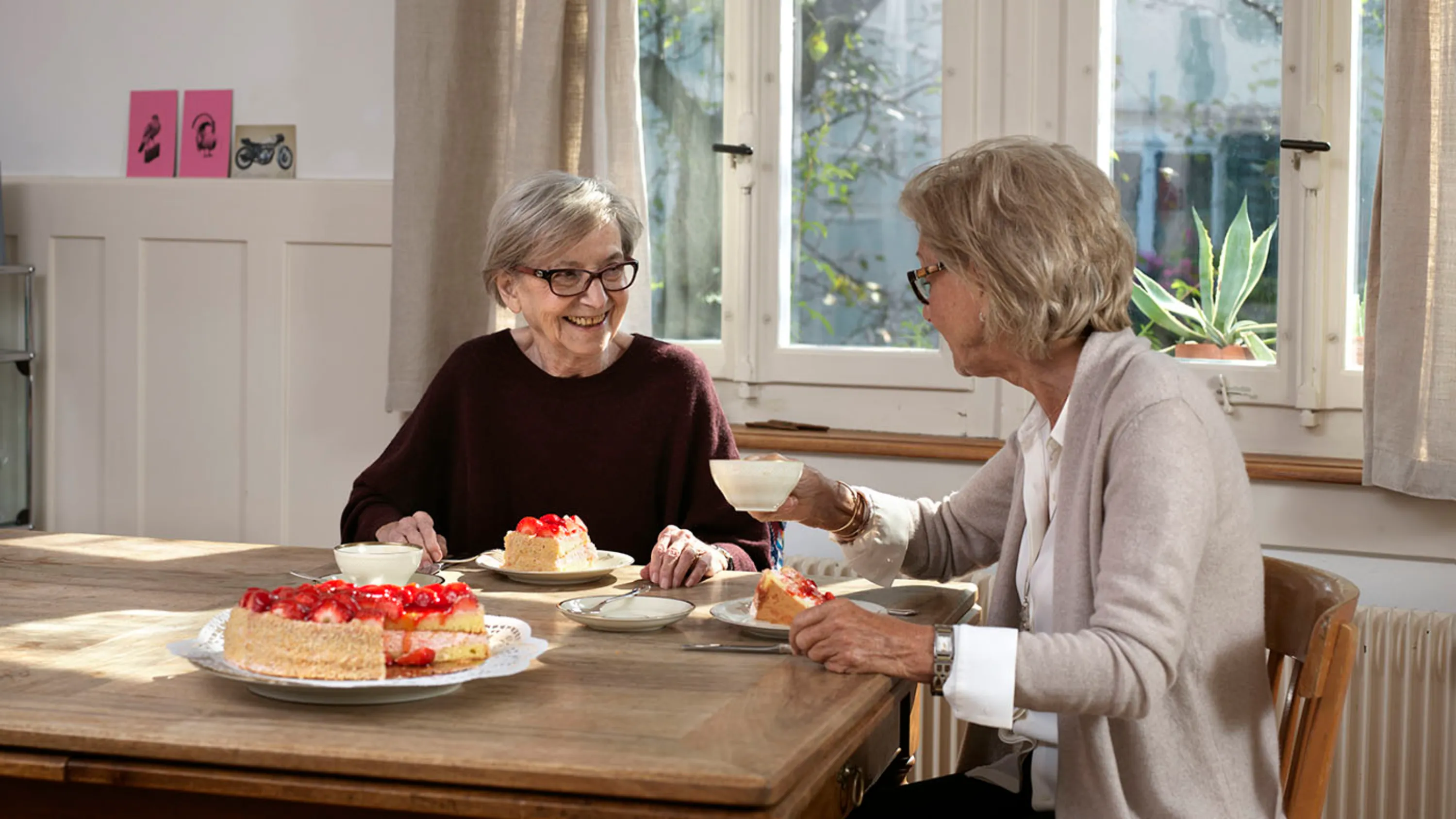 Zwei Damen sitzen am Tisch beim Geburtstagskuchen