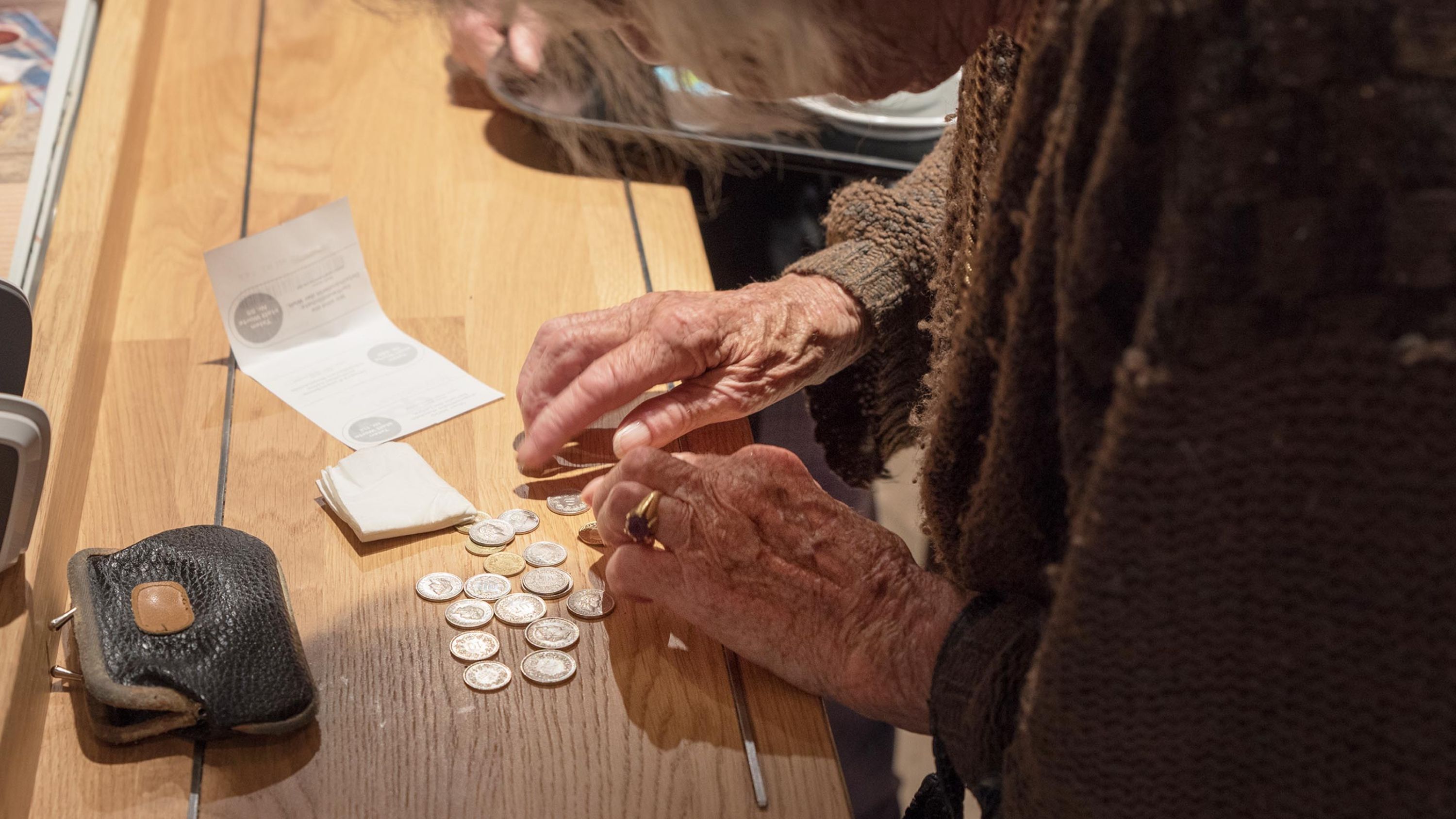 Una povera donna anziana paga con tante piccole monete.
