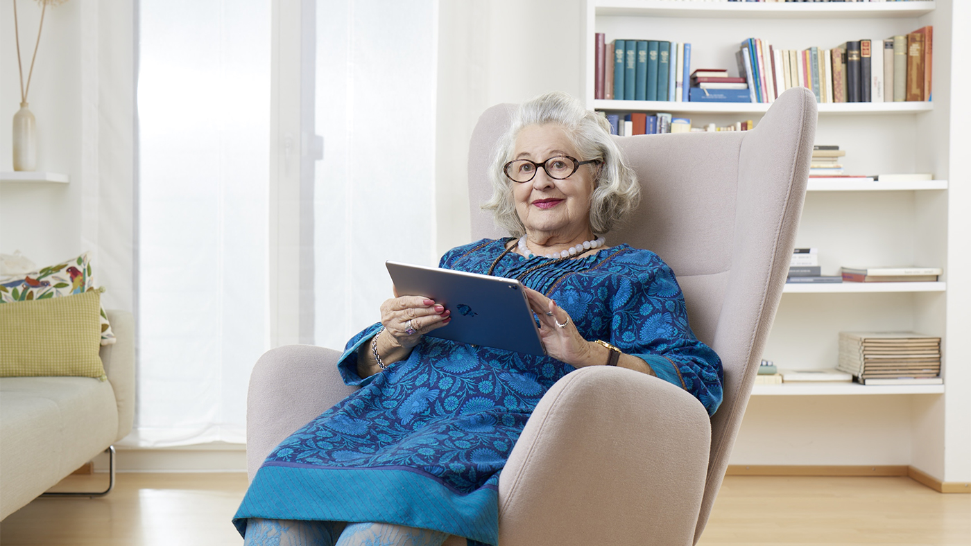 Eine Seniorin schaut sich zu Hause das Angebot von Pro Senectute auf ihrem Tablet an.