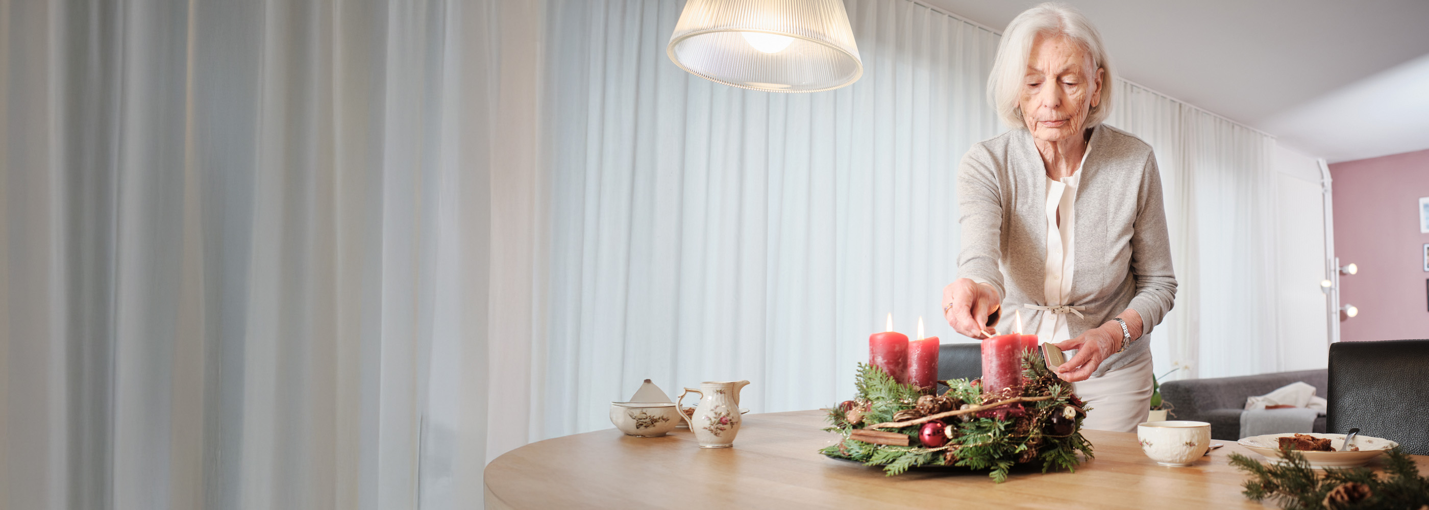 Signora anziana accende le candele della corona dell’Avvento.
