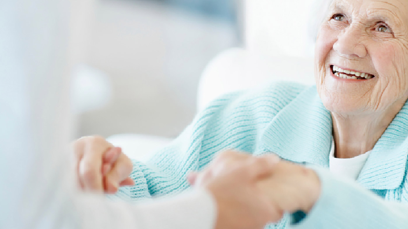 Freundliche Seniorin bekommt Hilfe beim Aufstehen.