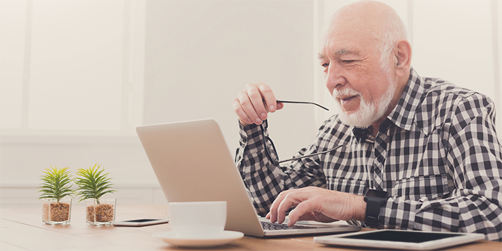 Mann am Laptop Zuhause am Wohnzimmertisch