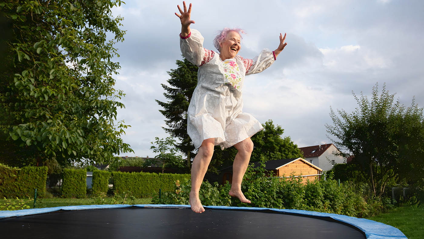Un'anziana felice che rimbalza sul trampolino.
